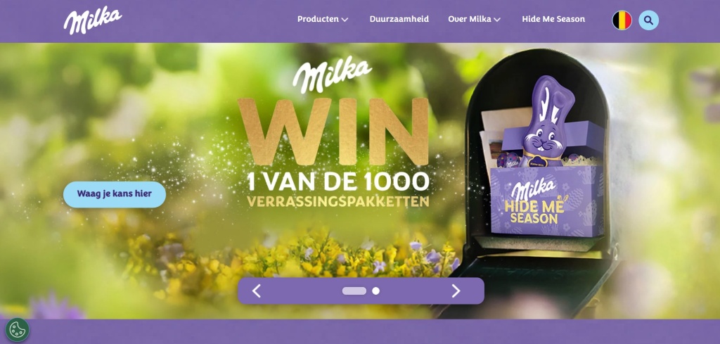  Баннер Milka с лиловым подарочным набором и логотипом на фоне солнечного весеннего луга.